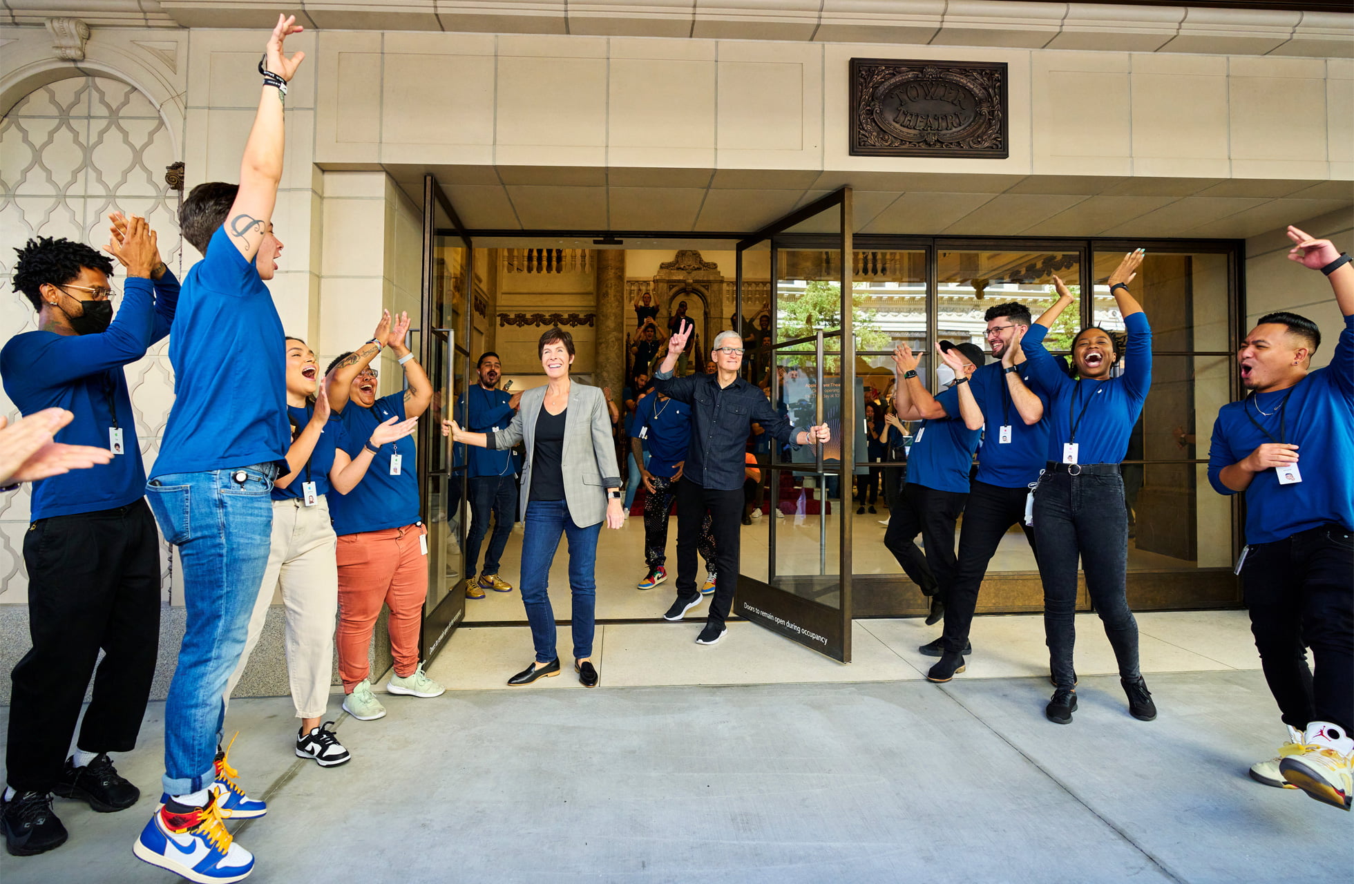 Apple’s CEO, Tim Cook (center right), and senior vice president of Retail + People, Deirdre O’Brien (center left), welcome the first customers to Apple Tower Theatre. 