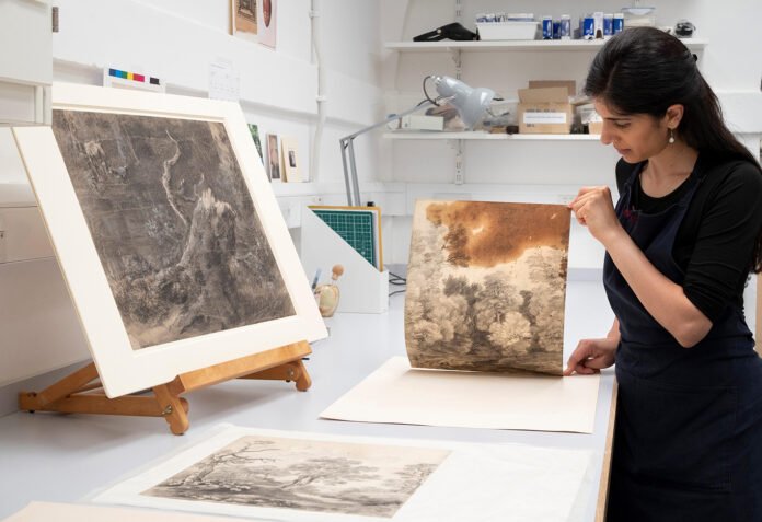 Paper Conservator Puneeta Sharma examines Thomas Gainsborough’s Trees beside a lake, c.1748-50, which features a large oil stain from Gainsborough’s studio © Royal Collection Trust/© Her MajestyQueen Elizabeth II 2021