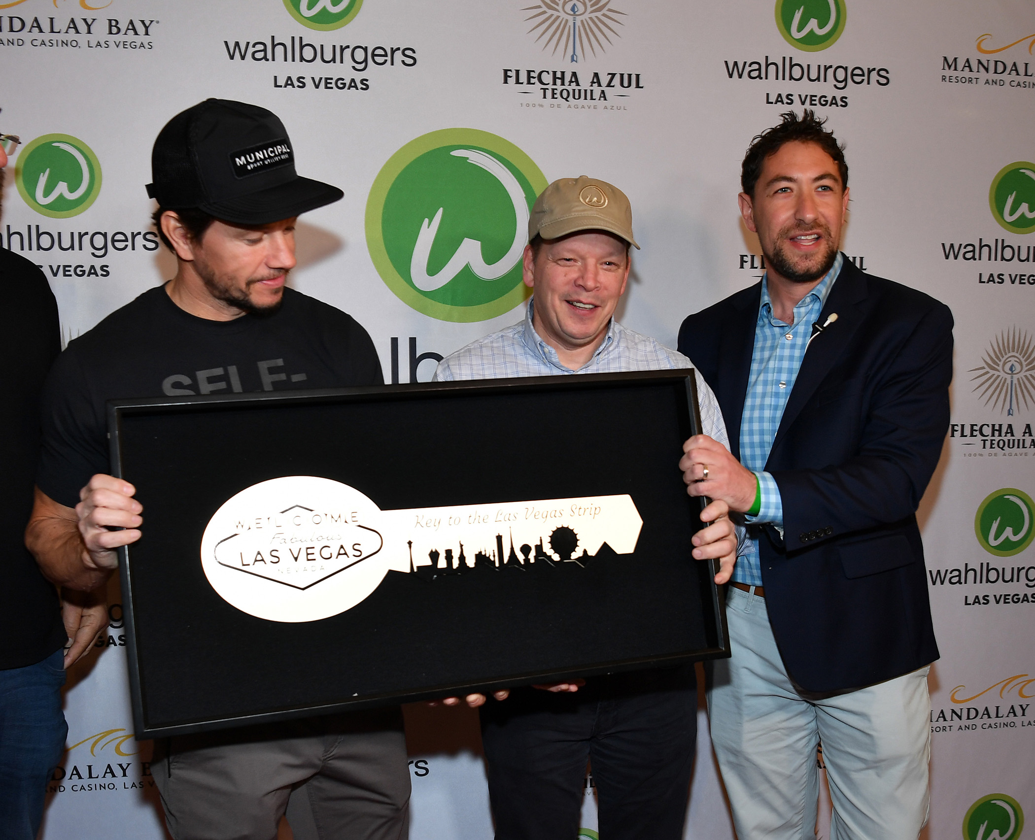 LAS VEGAS, NEVADA - MARCH 27: County Commissioner Michael Naft (R) presents Mark Wahlberg and Chef Paul Wahlberg with keys to the Las Vegas Strip at the grand opening of Whalburgers At Mandalay Bay Resort And Casino on March 27, 2023 in Las Vegas, Nevada.