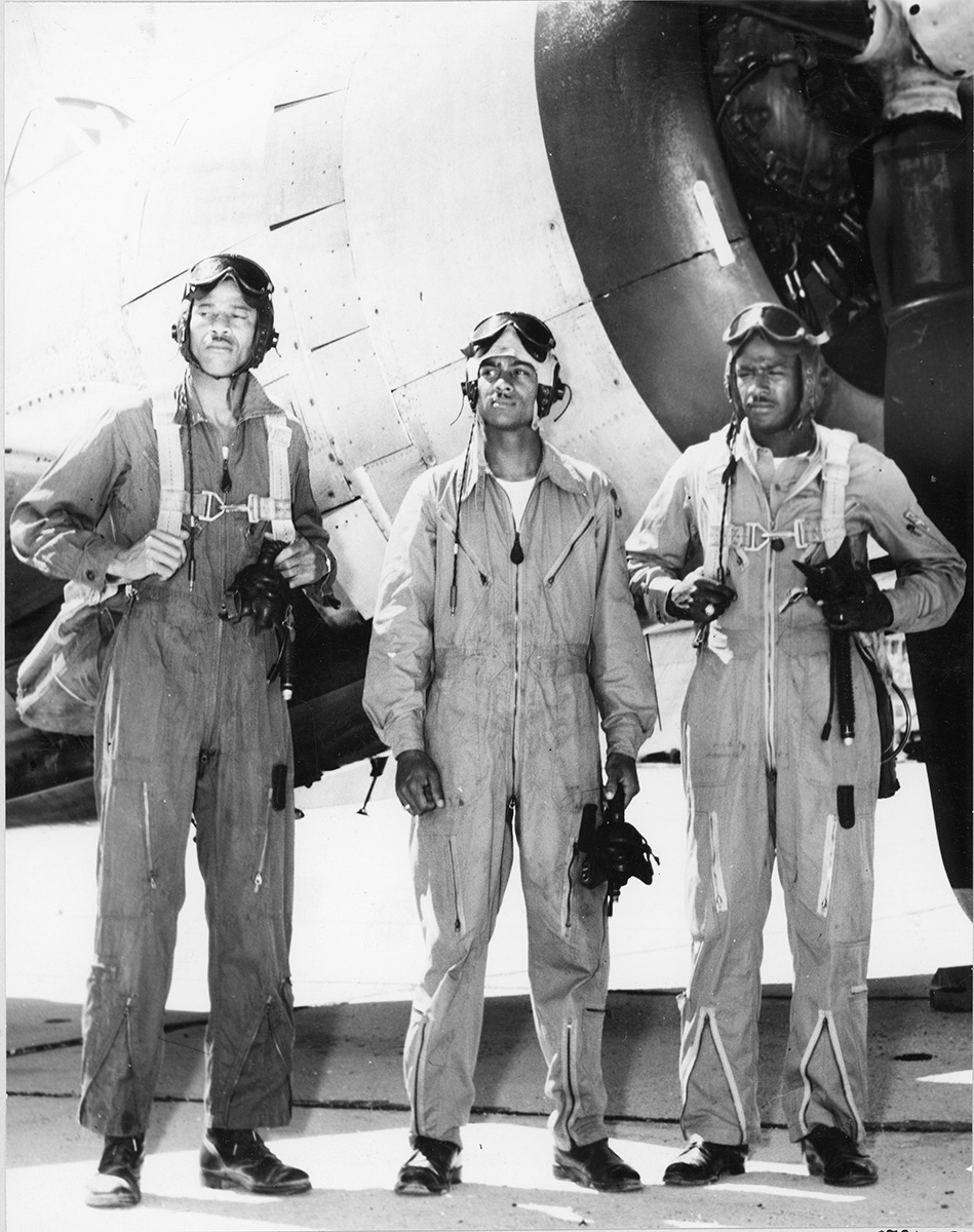 Henry Thaddeus Stewart and James Harvey (second and third, from L to R) stand next to a military plane. 