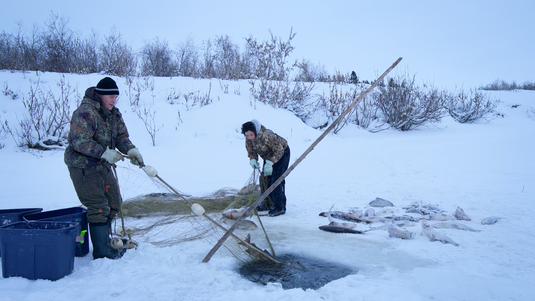 Chip Hailstone and his daughter, Carol pull their net out of the ice, full of fish.