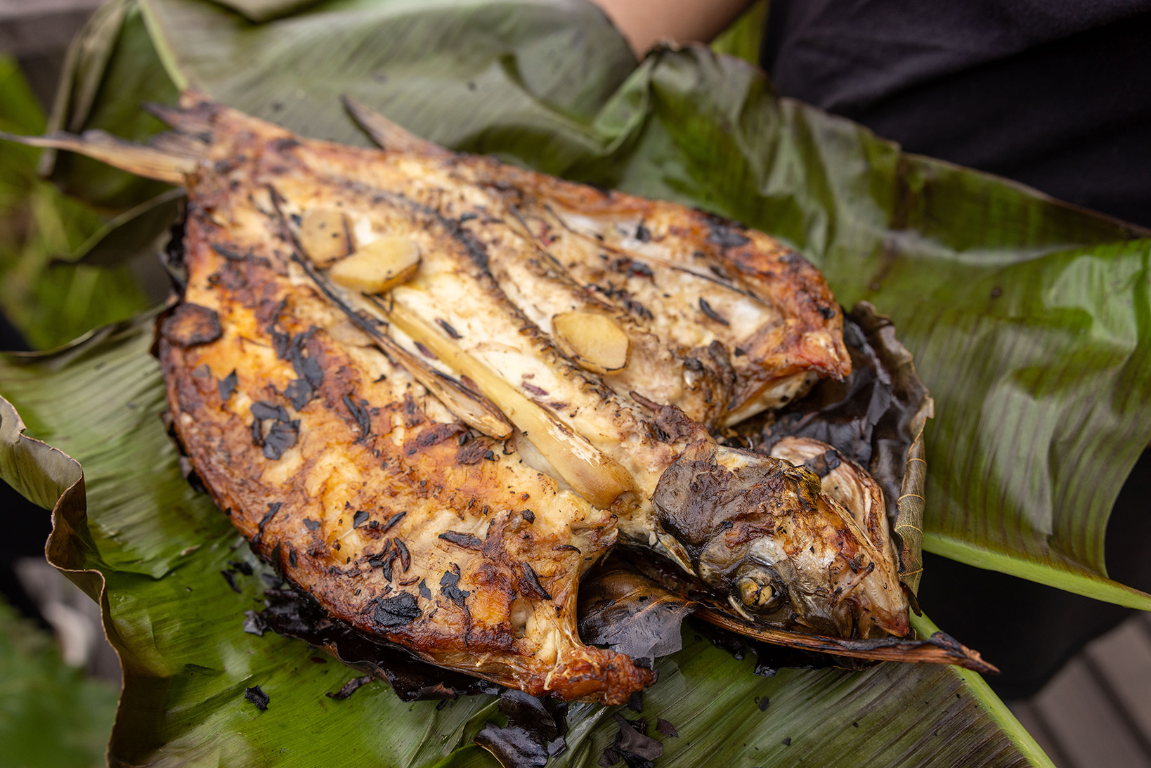 Close-up of cooked Ikan Semah dish wrapped in leaves.